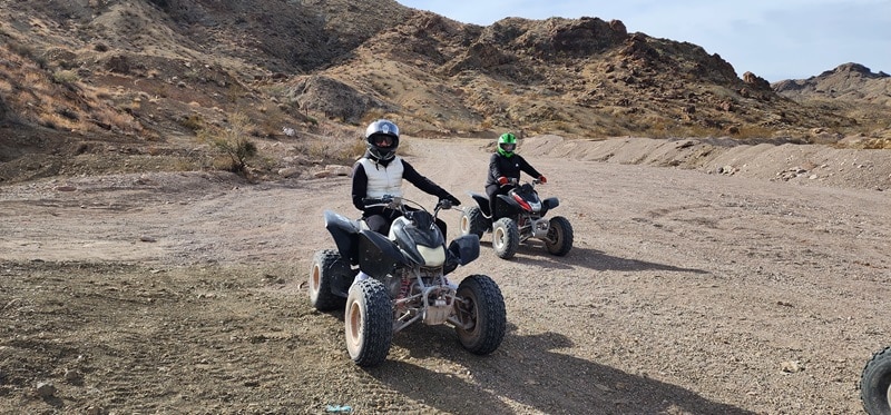 Two people riding ATVs at Awesome Adventures.